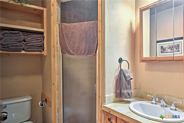 bathroom featuring toilet, vanity, and tiled shower