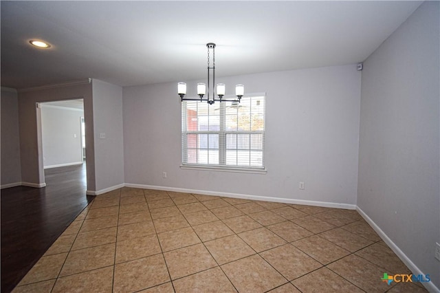 unfurnished dining area featuring tile patterned floors, crown molding, and an inviting chandelier