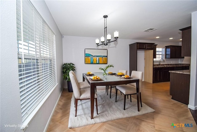 dining area with light parquet floors, sink, and a chandelier