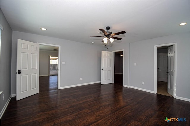 unfurnished bedroom with a walk in closet, ceiling fan, and dark wood-type flooring