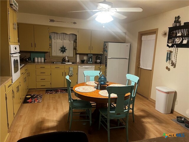 kitchen featuring white appliances, ceiling fan, sink, and light hardwood / wood-style flooring