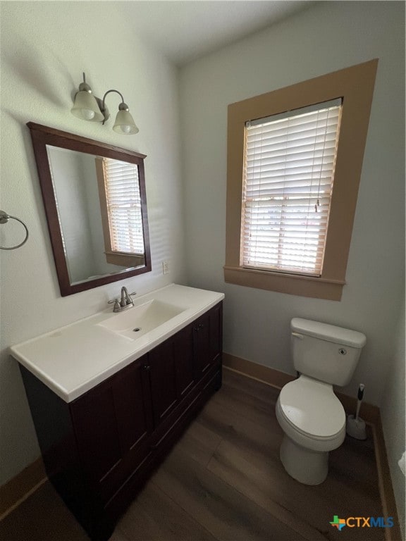 bathroom with a wealth of natural light, vanity, toilet, and hardwood / wood-style flooring