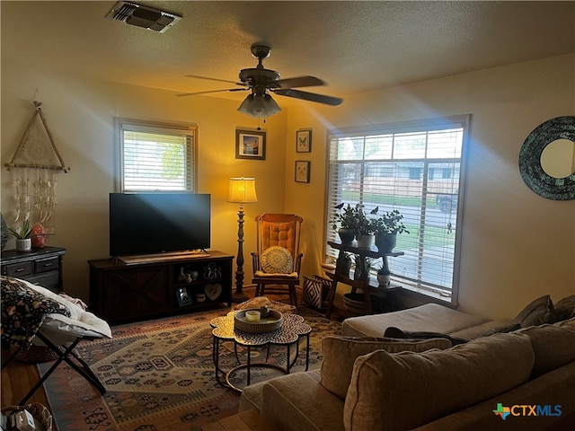 living room with hardwood / wood-style floors, ceiling fan, and a textured ceiling