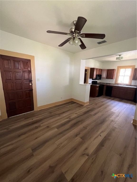 unfurnished living room with dark hardwood / wood-style flooring and ceiling fan