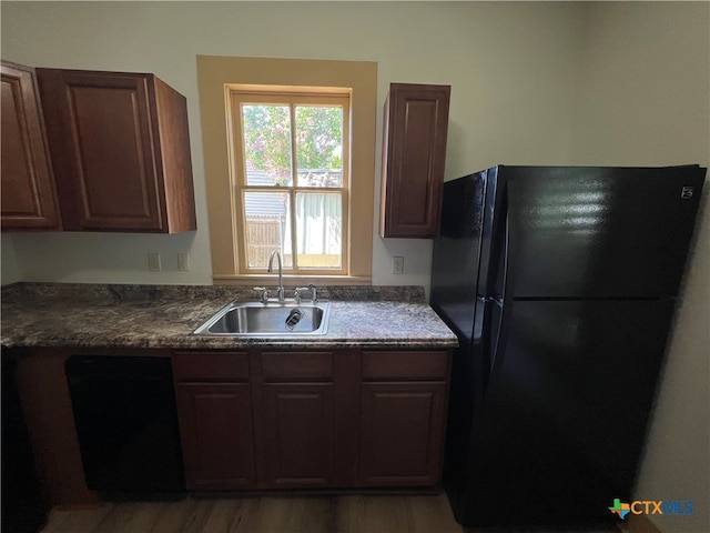 kitchen with black appliances, sink, dark brown cabinetry, and wood-type flooring