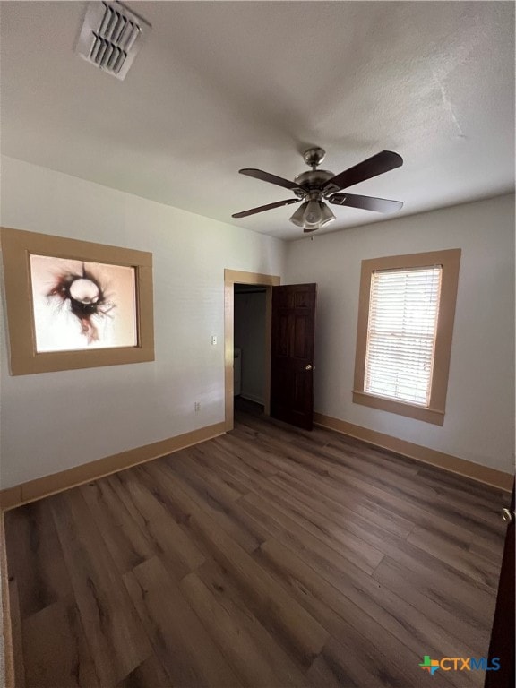 empty room with dark wood-type flooring, a textured ceiling, and ceiling fan