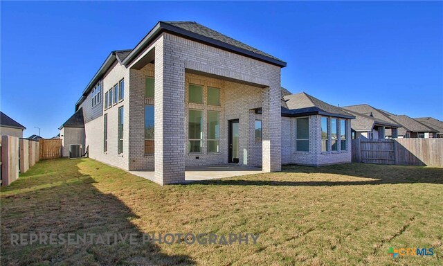 rear view of property with cooling unit, brick siding, a fenced backyard, and a lawn