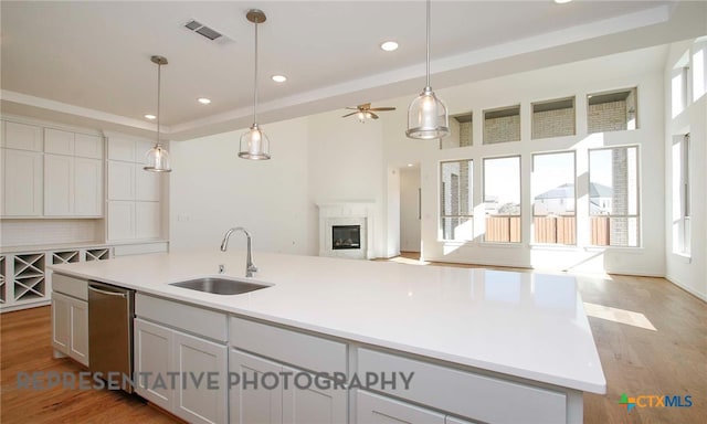 kitchen with light wood finished floors, visible vents, a wealth of natural light, a fireplace, and a sink