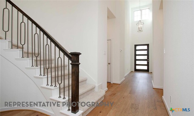 entrance foyer with baseboards, wood finished floors, a towering ceiling, and stairs