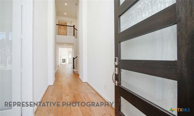 corridor with baseboards, stairway, recessed lighting, a towering ceiling, and wood finished floors