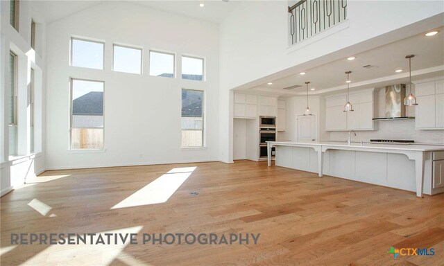 unfurnished living room with light wood finished floors, a high ceiling, and a sink