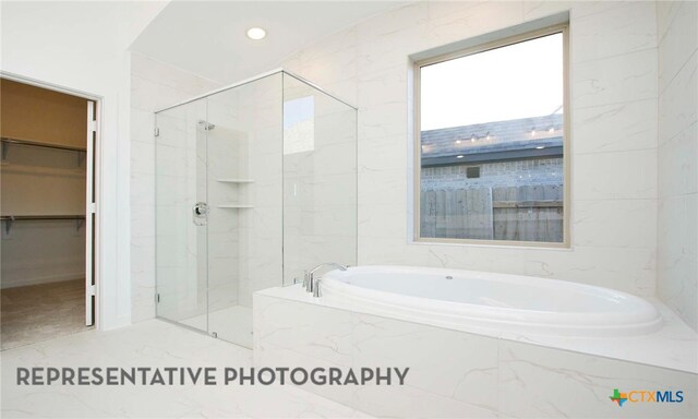 full bath with a marble finish shower, a bath, and a spacious closet