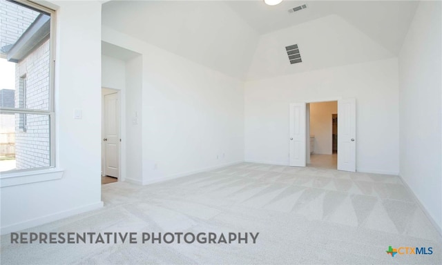 spare room featuring visible vents, high vaulted ceiling, a healthy amount of sunlight, and carpet flooring