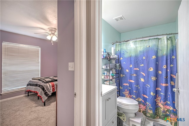 bathroom with a shower with shower curtain, vanity, toilet, and ceiling fan