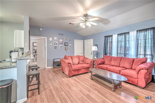 living room with light hardwood / wood-style floors, ceiling fan, lofted ceiling, and sink