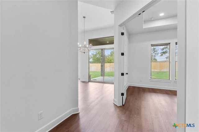 doorway to outside featuring dark wood-style floors, visible vents, baseboards, and a notable chandelier