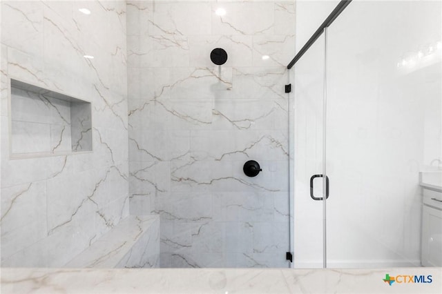 bathroom with vanity and a marble finish shower