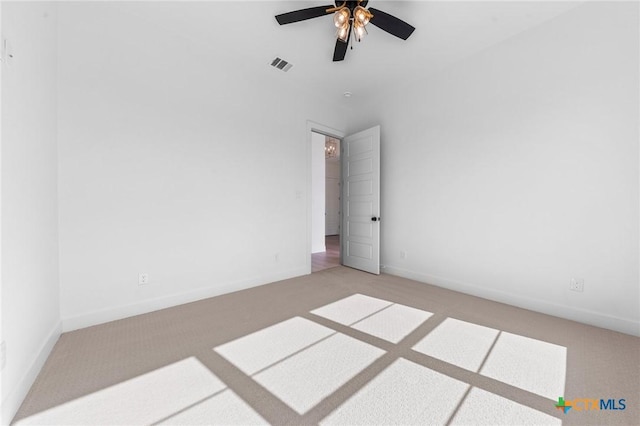 spare room with carpet floors, ceiling fan, visible vents, and baseboards