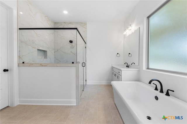 full bathroom featuring a soaking tub, a marble finish shower, vanity, and baseboards