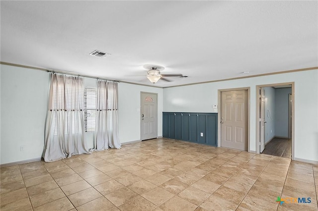spare room featuring visible vents, ornamental molding, baseboards, and ceiling fan