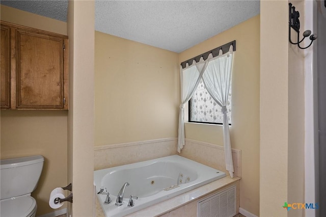 full bath featuring baseboards, a tub with jets, toilet, and a textured ceiling