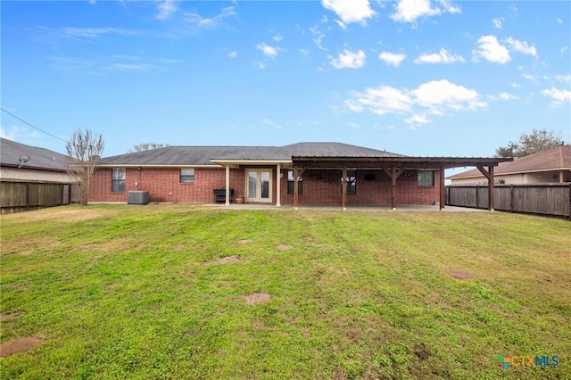 back of property featuring brick siding, a fenced backyard, central AC unit, a patio area, and a yard