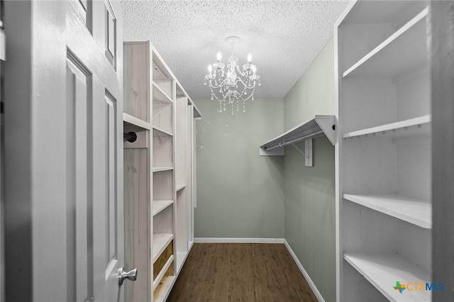 spacious closet with a chandelier and wood finished floors