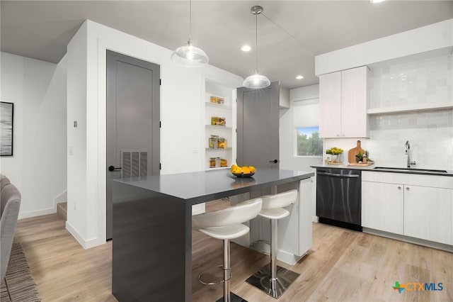 1208 N Academy Ave Unit 3203, New Braunfels, TX 78130 - kitchen with dishwasher, a sink, dark countertops, light wood-style floors, and a breakfast bar area