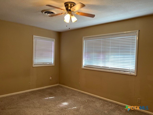 spare room with ceiling fan, carpet floors, and a textured ceiling