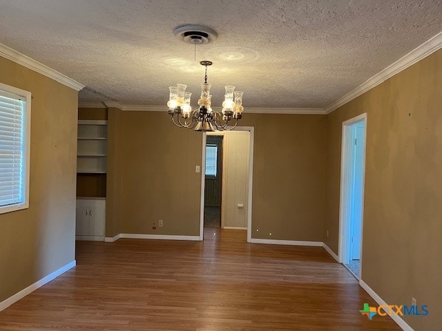 spare room with ornamental molding, wood-type flooring, a textured ceiling, and an inviting chandelier