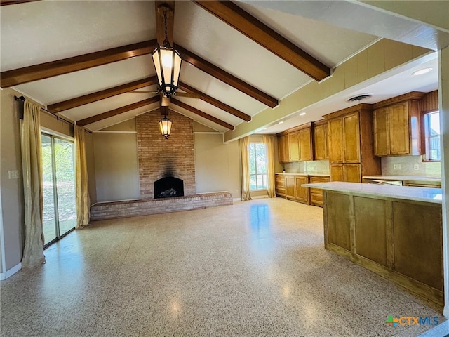 kitchen featuring light speckled floor, light countertops, ceiling fan, brown cabinetry, and vaulted ceiling with beams
