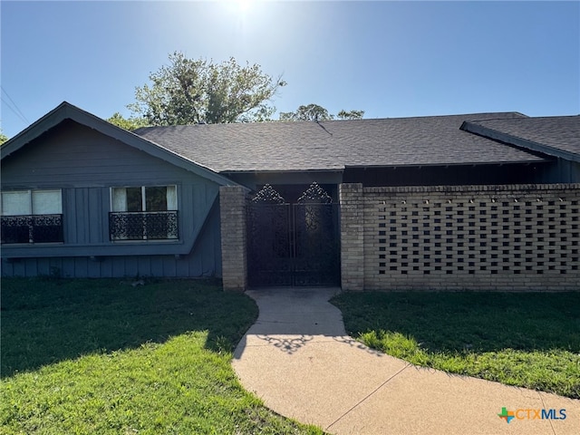 view of front of home with roof with shingles, board and batten siding, and a front lawn