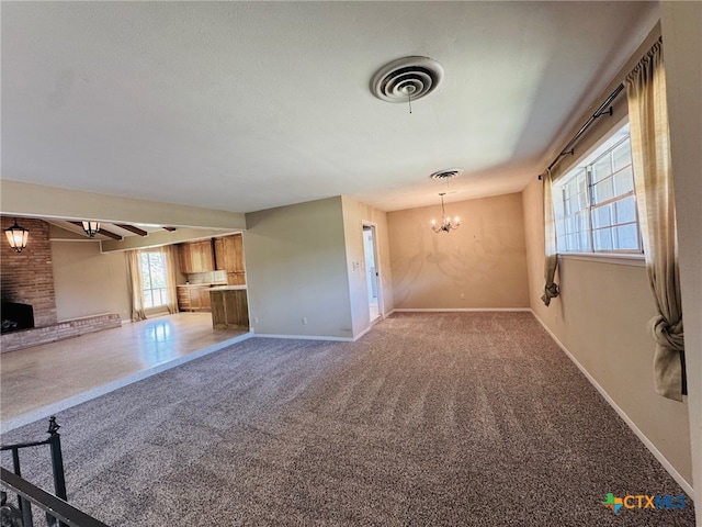 unfurnished living room with carpet, visible vents, a chandelier, a brick fireplace, and baseboards