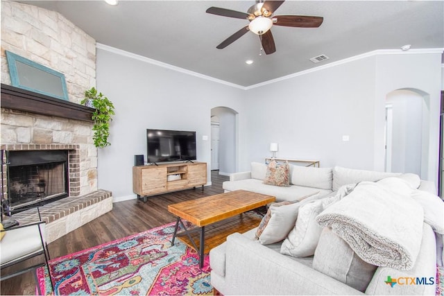 living area featuring arched walkways, crown molding, visible vents, a large fireplace, and wood finished floors