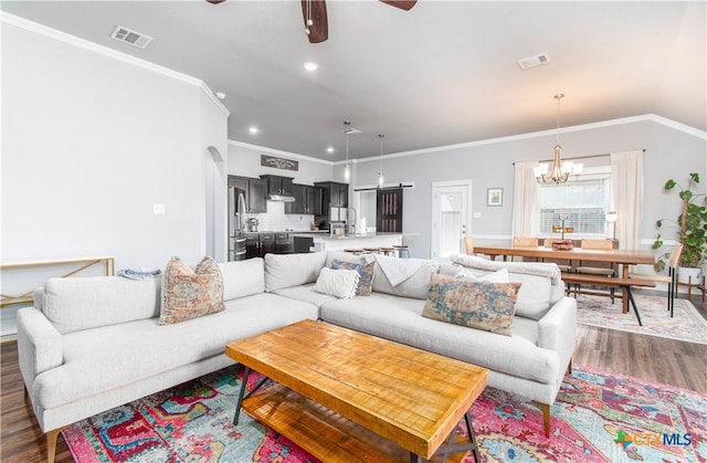 living room featuring arched walkways, ceiling fan with notable chandelier, dark wood-type flooring, visible vents, and crown molding