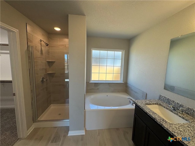 bathroom with vanity, plus walk in shower, hardwood / wood-style floors, and a textured ceiling