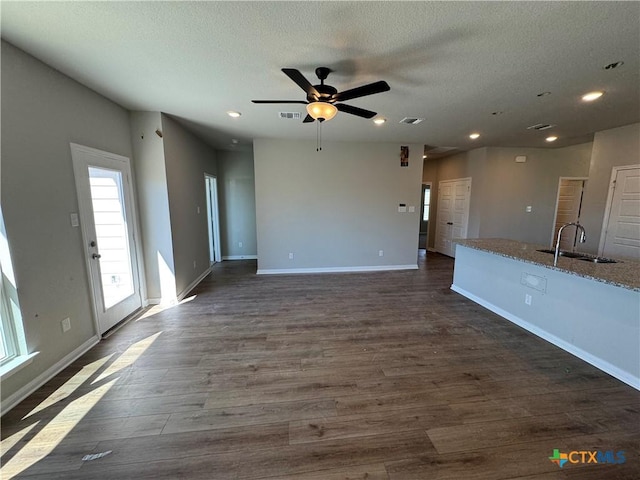 unfurnished living room featuring ceiling fan, dark hardwood / wood-style flooring, sink, and a textured ceiling