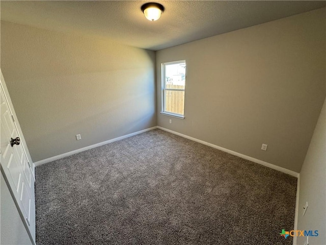 unfurnished room with a textured ceiling and dark colored carpet