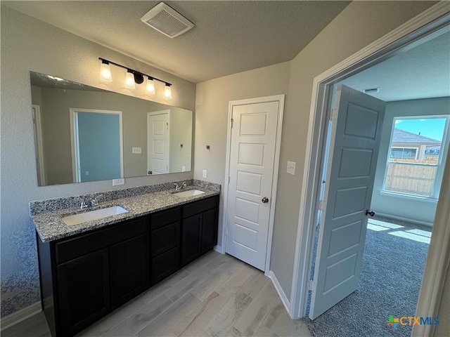 bathroom with hardwood / wood-style flooring, vanity, and a textured ceiling