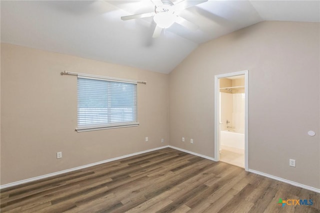 unfurnished bedroom with baseboards, vaulted ceiling, wood finished floors, and ensuite bathroom