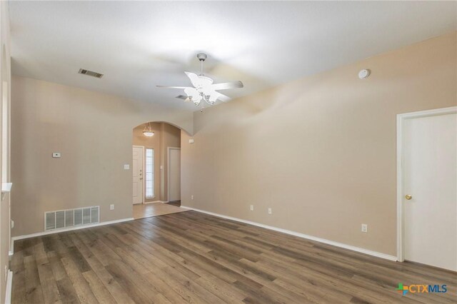 spare room with a ceiling fan, arched walkways, visible vents, and wood finished floors