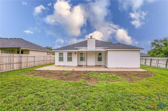 back of property featuring a lawn, a chimney, a patio area, and a fenced backyard