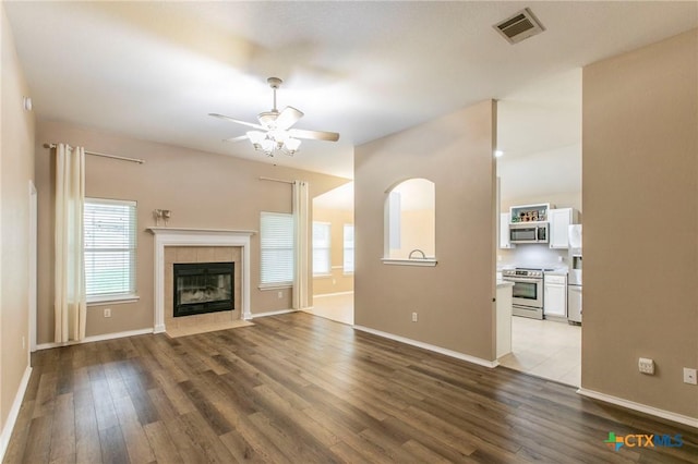 unfurnished living room with baseboards, ceiling fan, visible vents, and wood finished floors