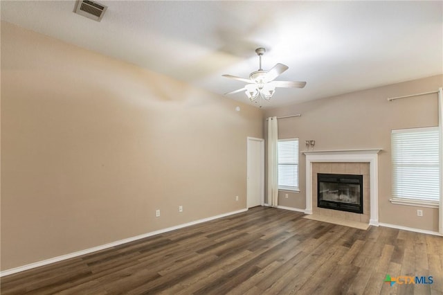 unfurnished living room with a fireplace, a ceiling fan, baseboards, wood finished floors, and visible vents