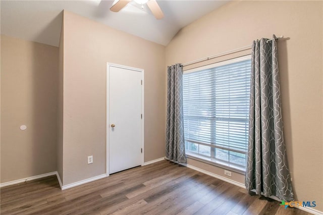 spare room featuring vaulted ceiling, baseboards, a ceiling fan, and wood finished floors
