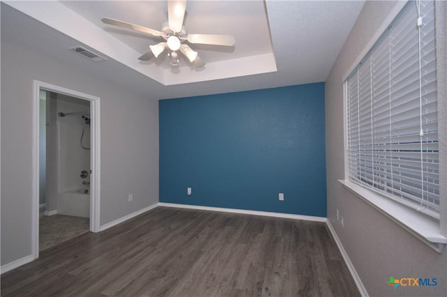 1614 Twisted Oak Dr, Temple, TX 76502 - unfurnished bedroom with wood finished floors, a tray ceiling, baseboards, and a ceiling fan