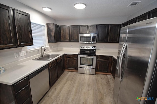 1614 Twisted Oak Dr, Temple, TX 76502 - kitchen featuring stainless steel appliances, a sink, light wood-type flooring, dark brown cabinetry, and light countertops