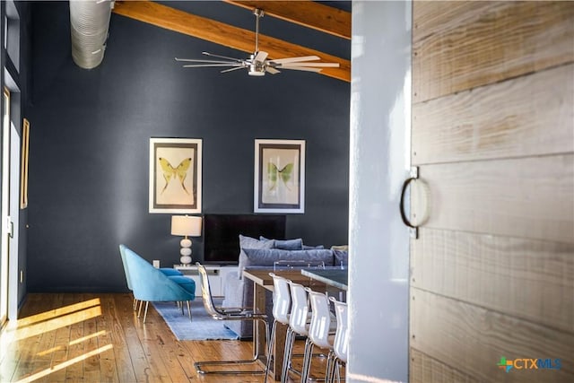 dining space featuring hardwood / wood-style floors, vaulted ceiling with beams, and ceiling fan