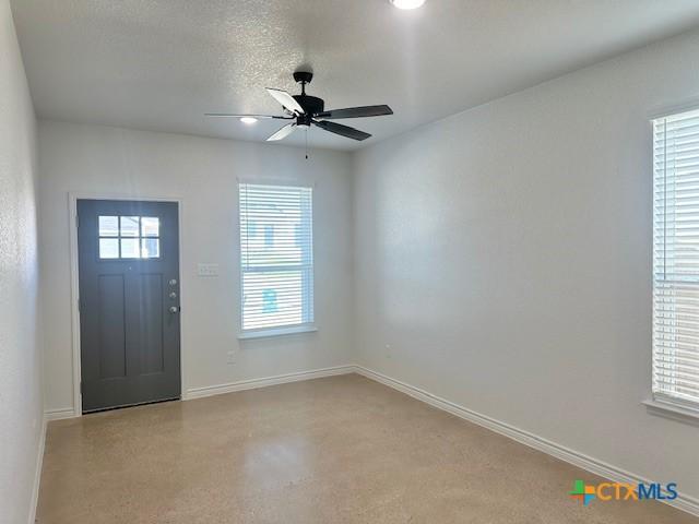 foyer entrance featuring a textured ceiling, a ceiling fan, and baseboards