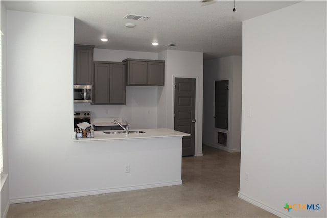 kitchen with a textured ceiling, stainless steel appliances, and sink